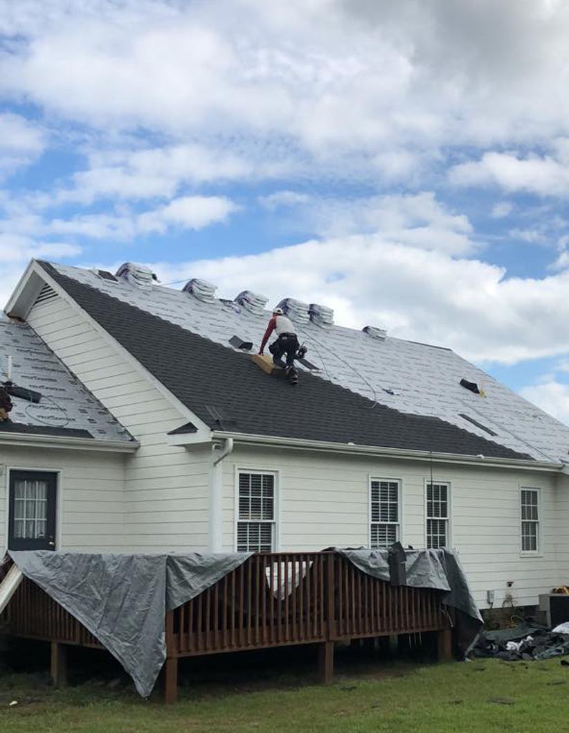 A man on top of the roof of a ranch home, or information on a roofing company near me - Thurston Roof