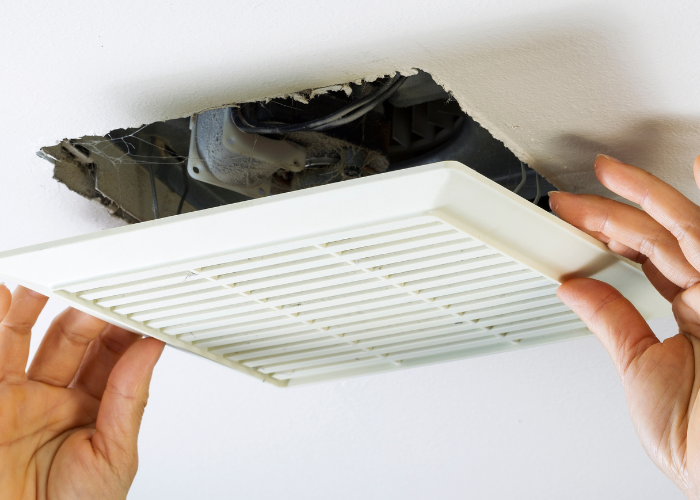 Hands gently removing a ceiling vent
