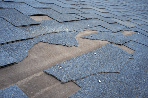A section of a roof that needs repair due to missing and broken shingles
