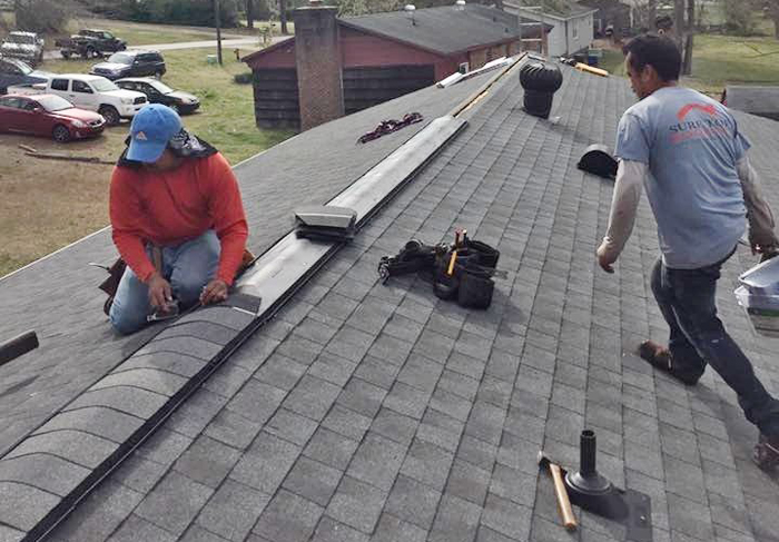 Thurston Roof of Raleigh team on a roof placing ridge capping to reduce how often the homeowner must replace the roof.